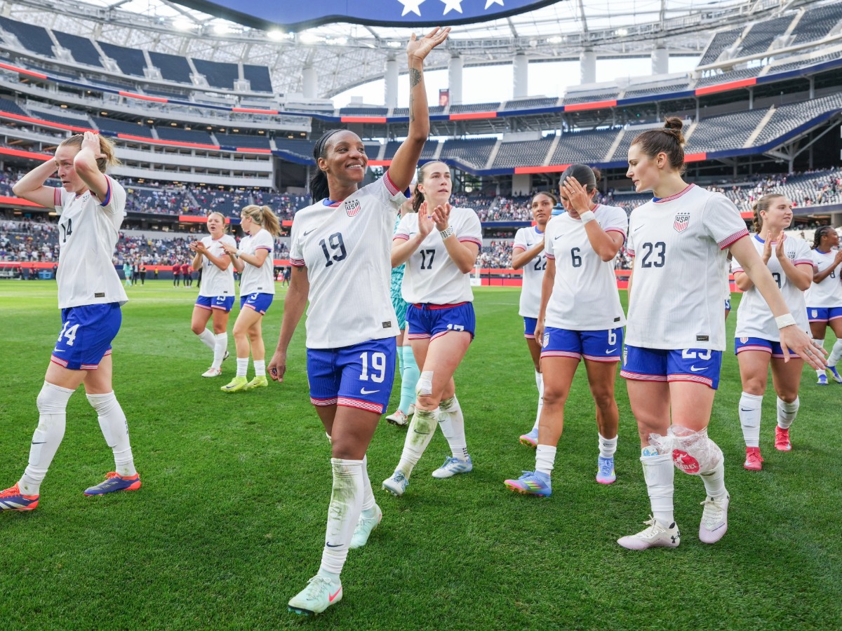 Crystal Dunn (#19) camina por el campo saludando a la afición junto a sus compañeras de equipo.