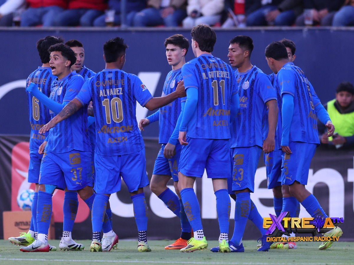 Jugadores de las Chivas, incluyendo a Armando González (#34), se reúnen en el campo tras una jugada clave.