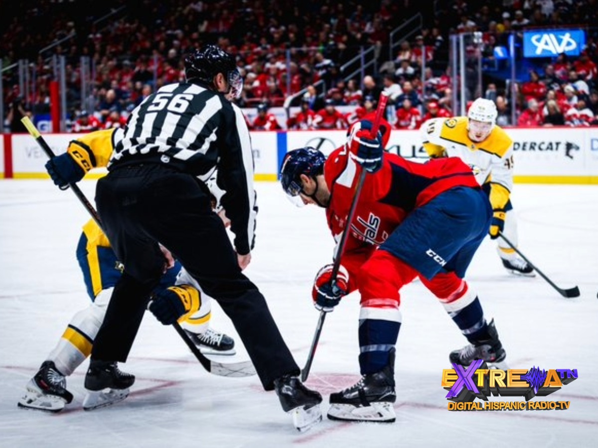Jugadores de los Capitals y Predators disputando un face-off frente al árbitro en el hielo.