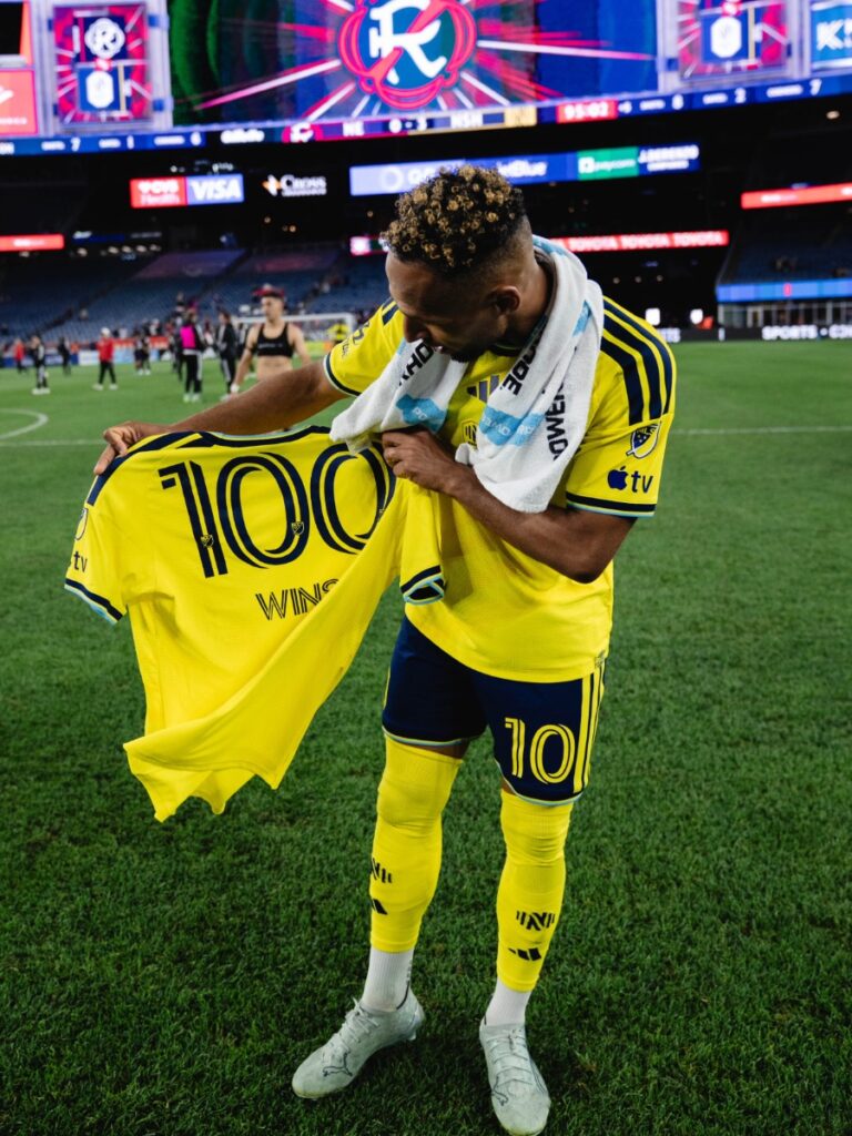 Hany Mukhtar sosteniendo la camiseta conmemorativa de las 100 victorias de Nashville SC
