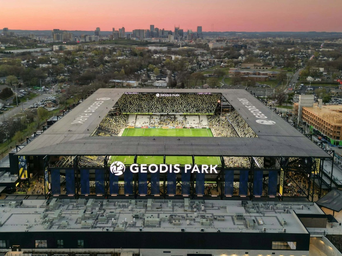 Vista aérea del Geodis Park en Nashville con el horizonte de la ciudad al fondo durante el atardecer.