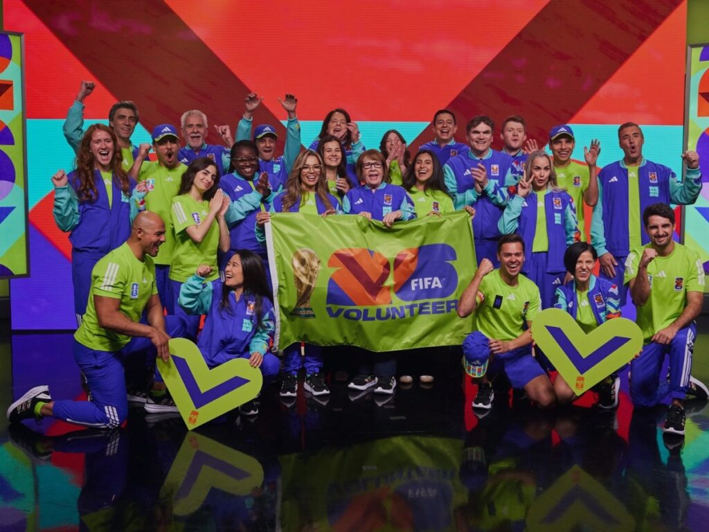 Voluntarios de la Copa Mundial 2026 posando con el uniforme oficial y el trofeo