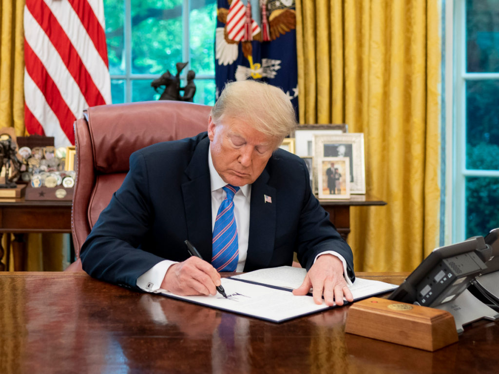 Donald Trump firmando una orden relacionada con bancos e inmigración