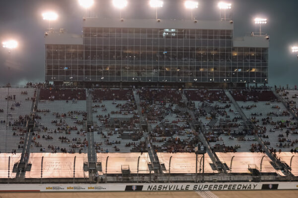 Aficionados resguardándose en la grada principal iluminada del autódromo de Nashville tras la lluvia
