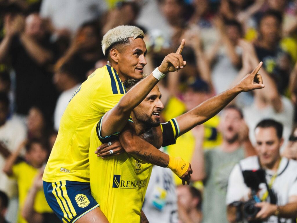 Andy Nájar celebra sobre la espalda de Hany Mukhtar señalando al cielo tras marcar un gol decisivo
