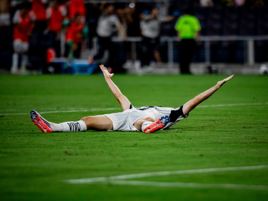 Hugo Cuypers tendido en el pasto con los brazos extendidos celebrando el gol del triunfo en tiempo añadido