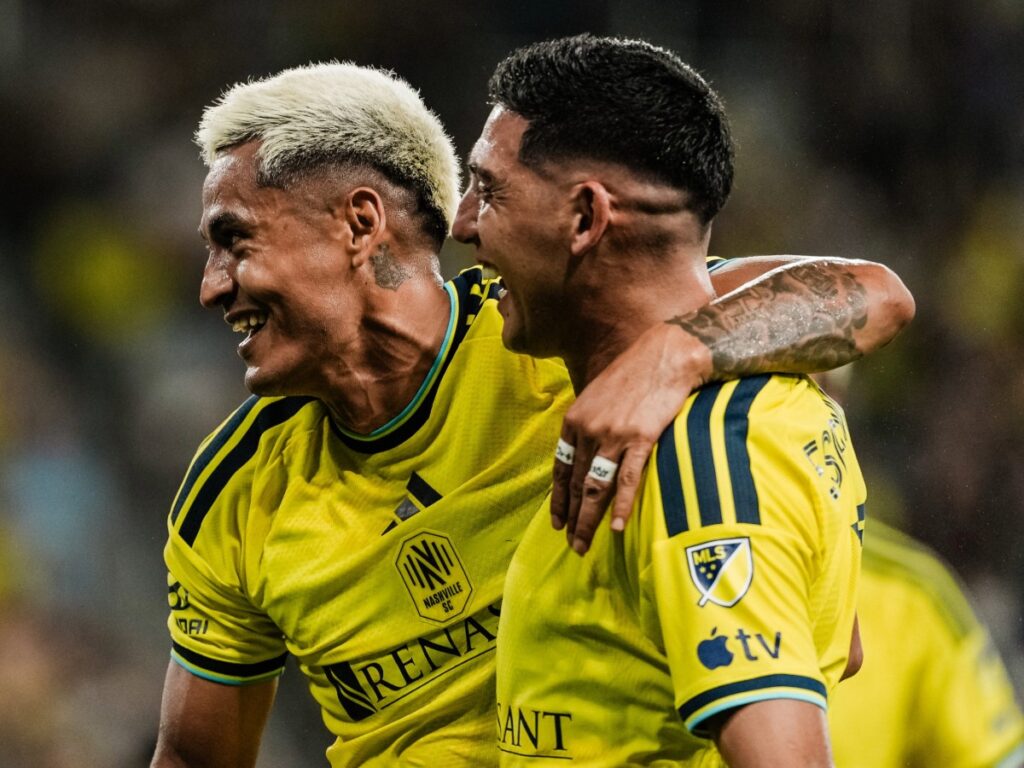 Andy Nájar sonríe abrazando a Cristian Espinoza en el terreno de juego