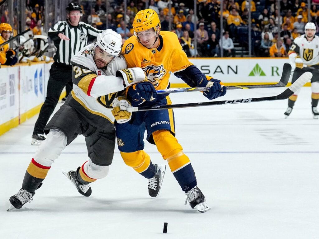 Brady Skjei forcejea cuerpo a cuerpo con un atacante de Vegas disputando el disco en el centro del hielo