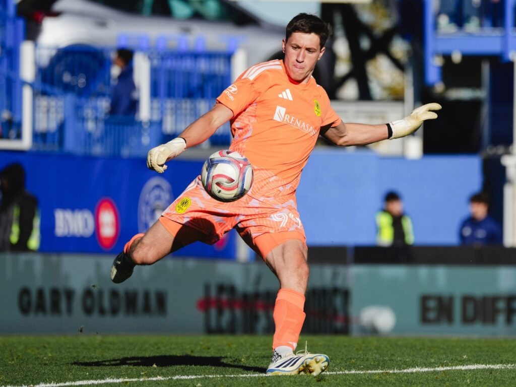 Brian Schwake despeja el balón con pierna derecha resguardando el arco en Canadá