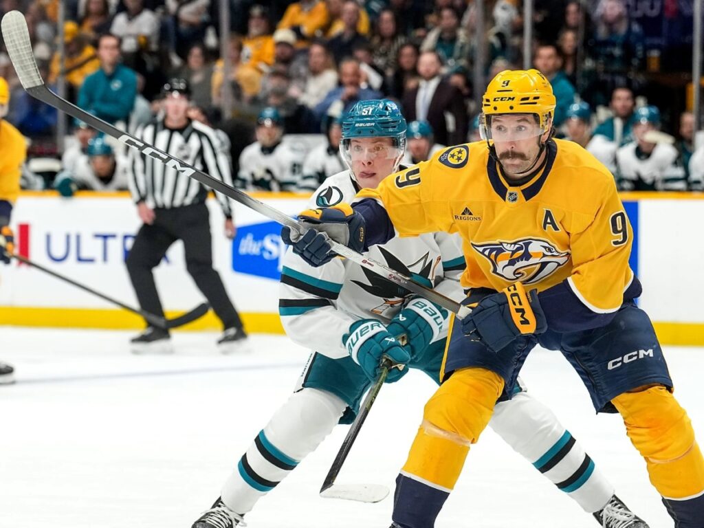 Filip Forsberg cubre el disco en la pista frente al acoso del zaguero de San Jose Sharks